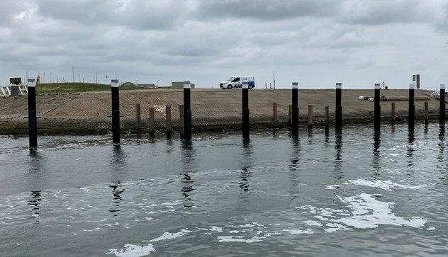 stalen palen geleidewerk met daarachter houten palen golfbrekers