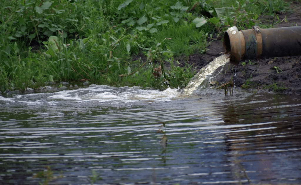 Foto van een buis die water afvoert in de sloot.
