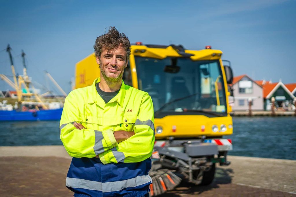 Foto van de campagne over werken op Texel. Een medewerker staat bij de veegwagen.